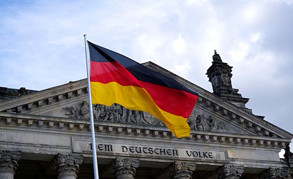 German national flag waving in front of the Reichstag building in Berlin, a symbol of democracy.